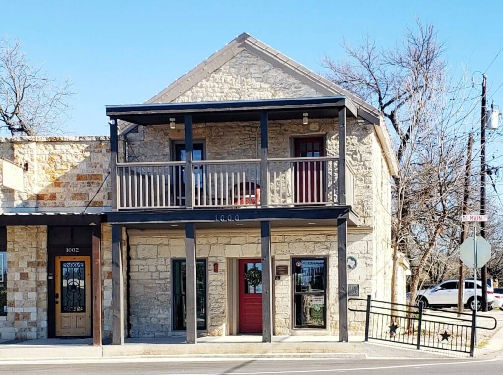 Two-story limestone building with balcony and red door