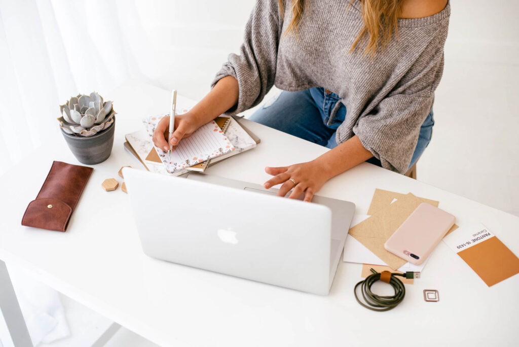 Woman planning at desk with laptop and notebook