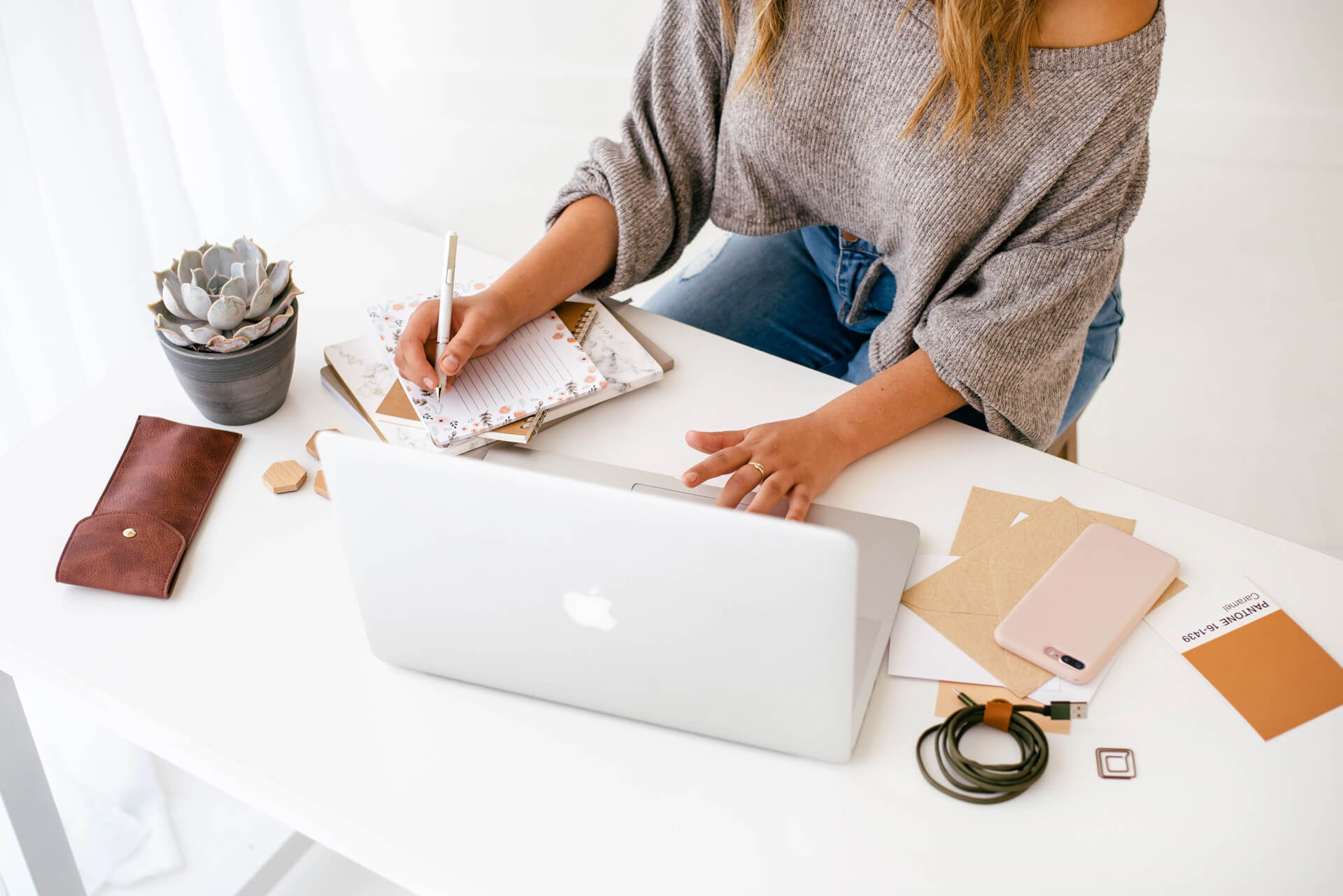 Woman planning at desk with laptop and notebook