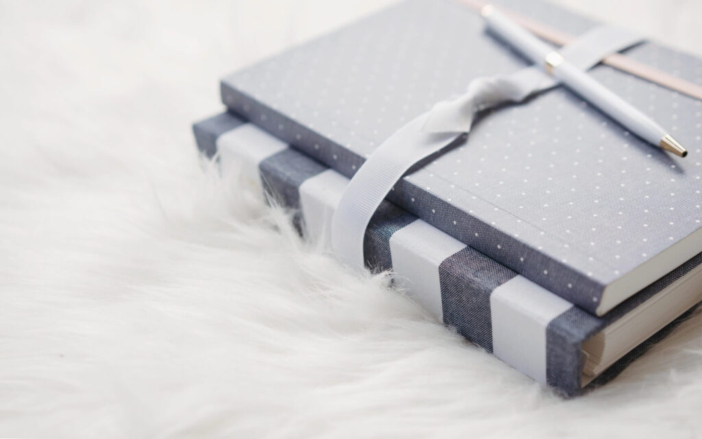 Gray polka-dot notebooks with pen and ribbon on white fur