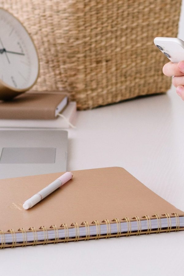 Person using smartphone at a desk with laptop