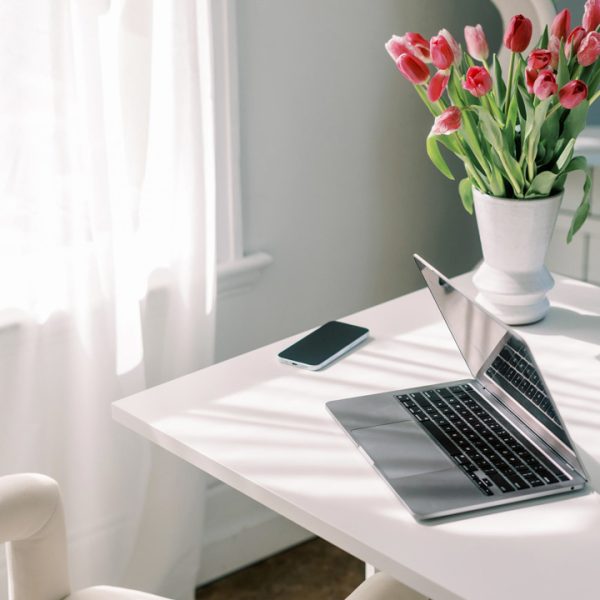 Sunlit desk with laptop and pink tulips