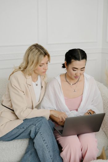 Two women reviewing a laptop together on a sofa
